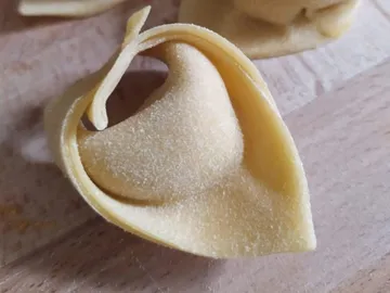 Pasta in the shape of a folded shell on wood.
