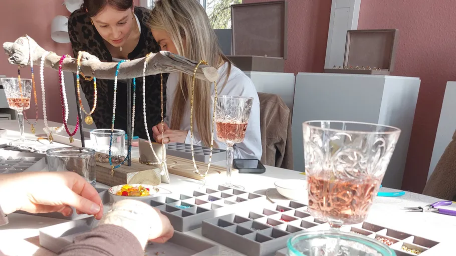 Two women crafting jewelry at a table.