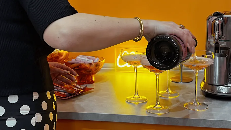 Person pouring champagne into glasses on counter.