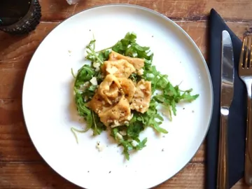 Pasta served on arugula, with wooden backing in the background.