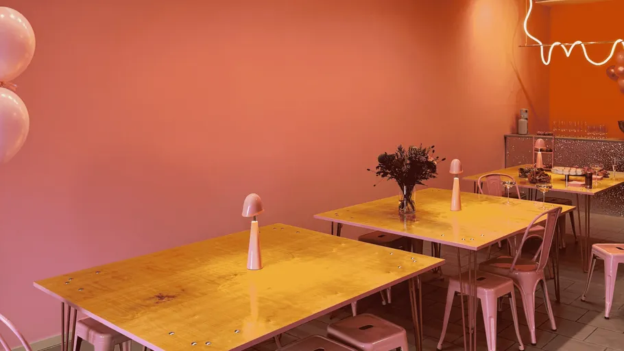 Pink dining area with wooden tables and chairs.
