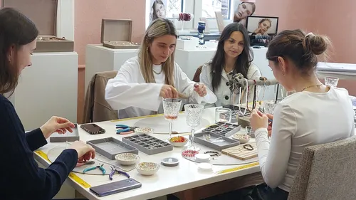 Frauen gestalten Schmuck an einem Werkstatttisch.