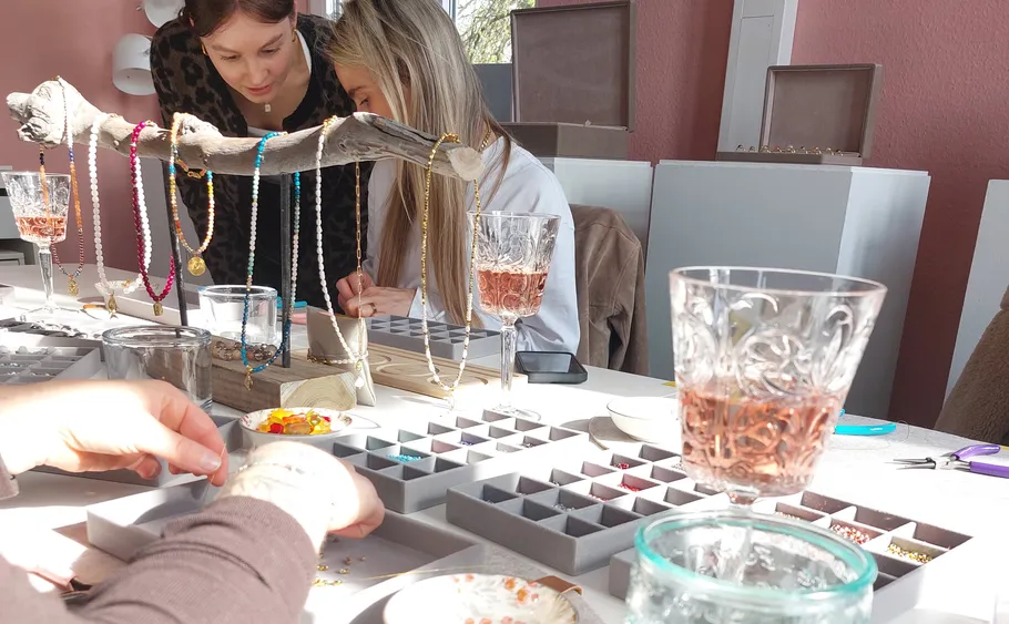 People creating jewelry in a bright room.