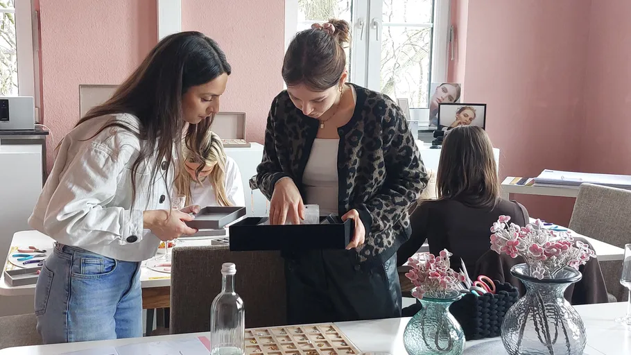 Zwei Frauen untersuchen Gegenstände im kreativen Arbeitsplatz.