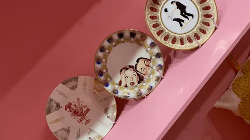 Three decorative plates on a pink shelf.