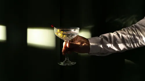 Hand holding a cocktail glass in dim light.