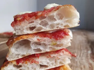 Stacked slices of bread with tomato sauce and cheese on top.