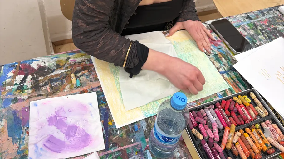 Person erstellt Kunst mit Pastellkreiden auf Papier.