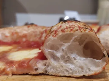 Pizza with crispy edges is laid out on a wooden board.