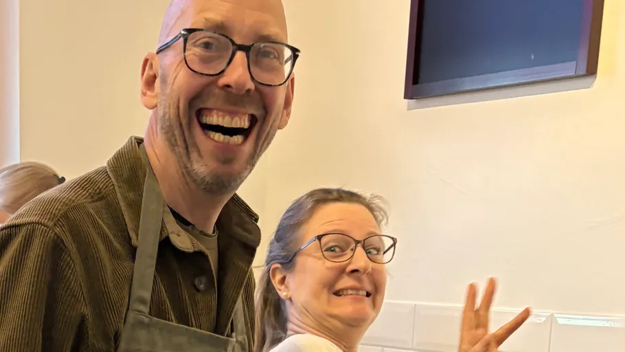 Two people smiling in a kitchen setting.