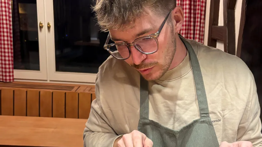 Man focusing on food preparation indoors.