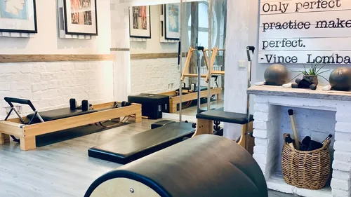 Yoga studio with reformer, art, and motivational quote.