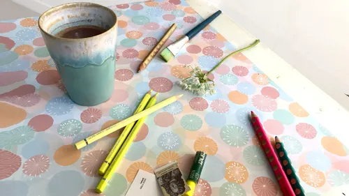 Cup and art supplies on colorful table.