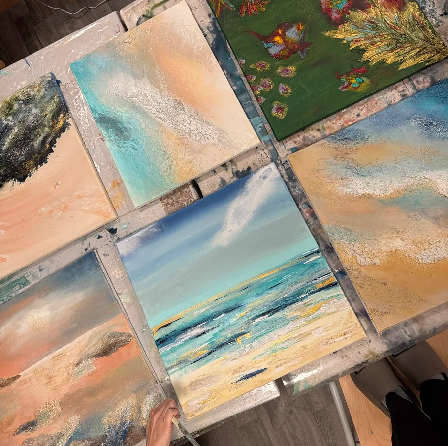 Multiple abstract paintings displayed on a table.