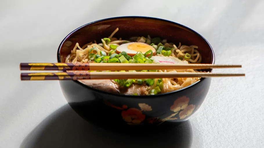 Bowl of ramen with chopsticks on table.