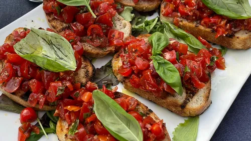 Bruschetta mit Tomaten und Basilikum auf Teller.