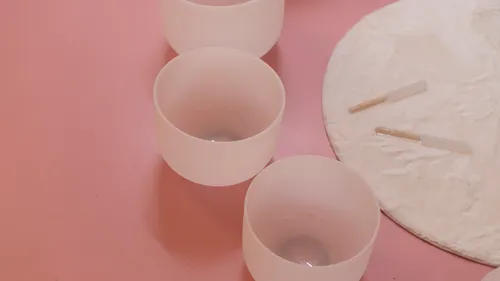 White bowls on pink surface, circular cloth.