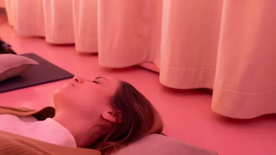 Frau liegt auf Matte in rosa Raum.