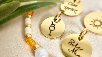 Gold charms with engraved designs and text.