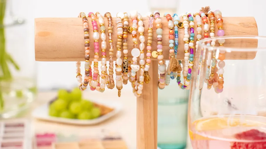 Colorful beaded bracelets displayed on wooden stand.