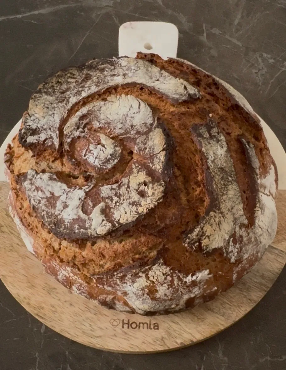 Round loaf of bread on wooden board.