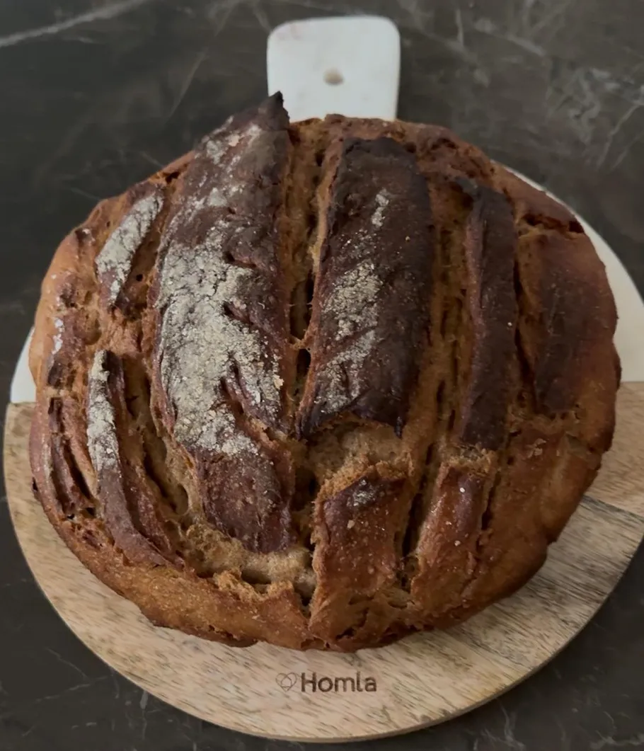 Round, crusty bread on a wooden board.