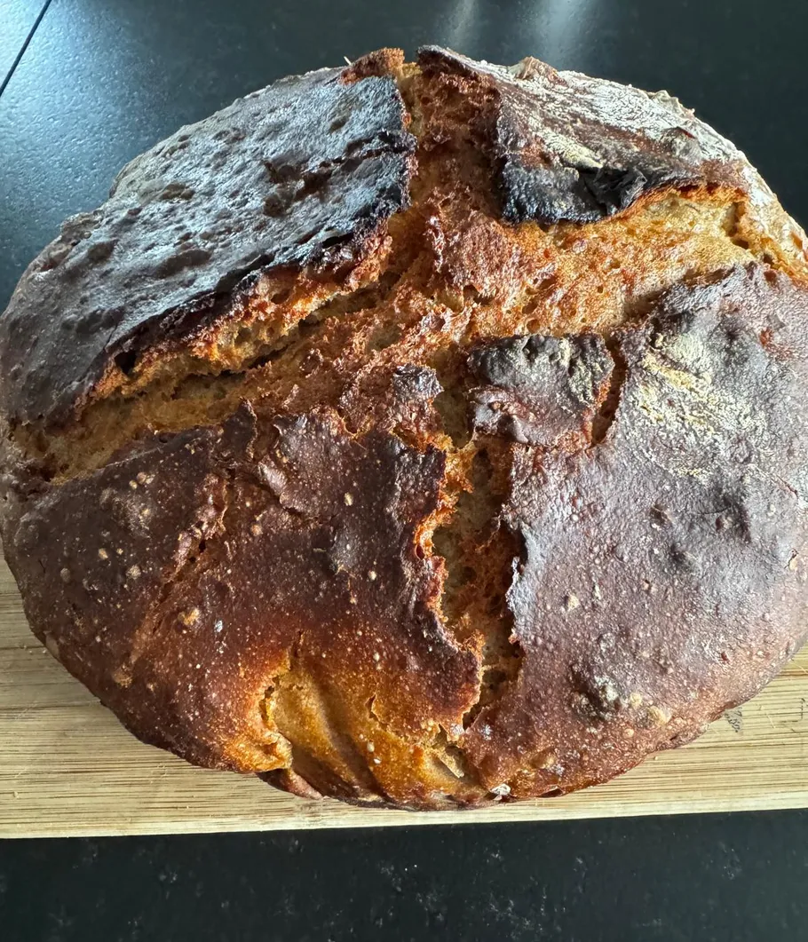Round loaf of bread on a wooden board.