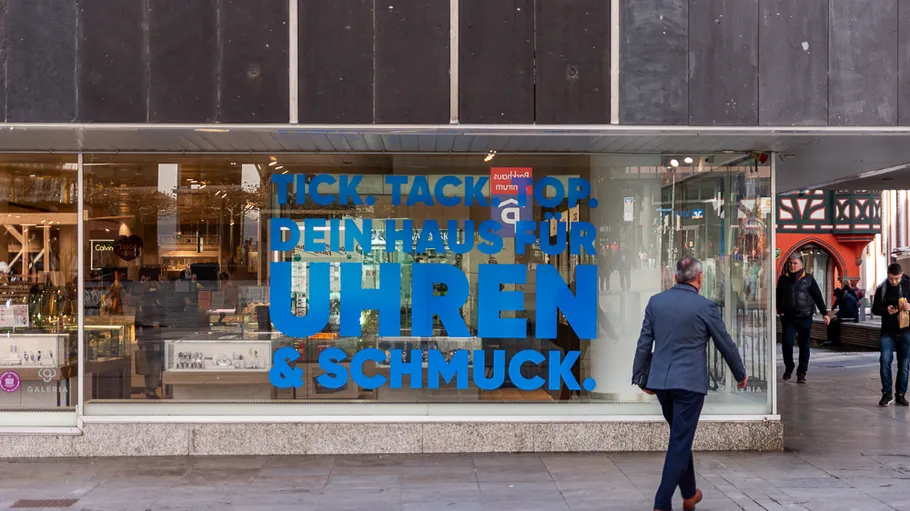 Mann geht an Schmuckladen-Schaufenster vorbei.