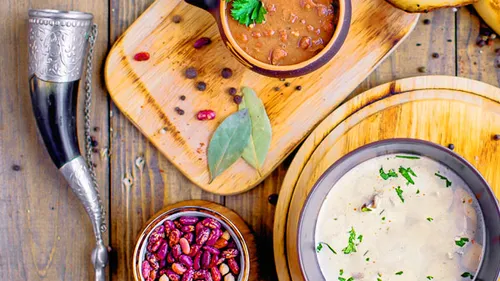 Bowls of soup and spices on wooden table.