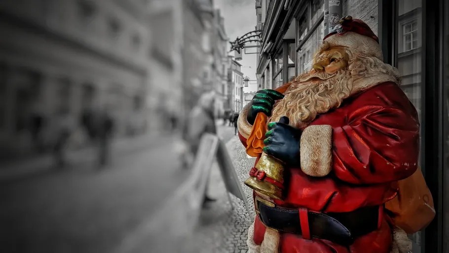 Santa statue holding bell, street background.