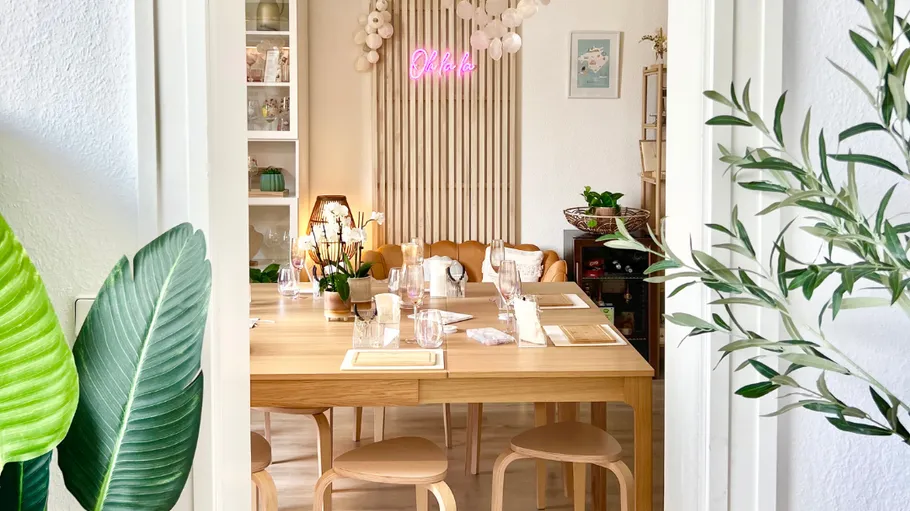 Dining area with wooden table and neon sign.