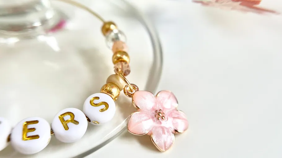 Perlenarmband mit rosa Blumenanhänger.