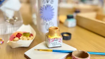 Gold paint and brush on table.