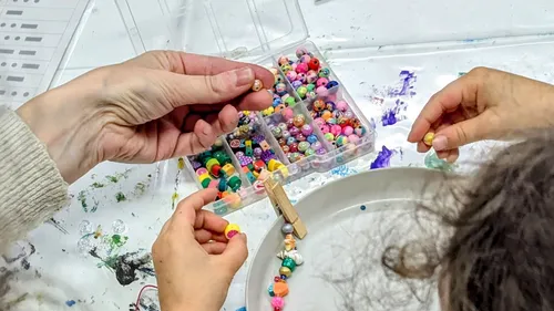 Hands decorating bracelet with colorful beads.