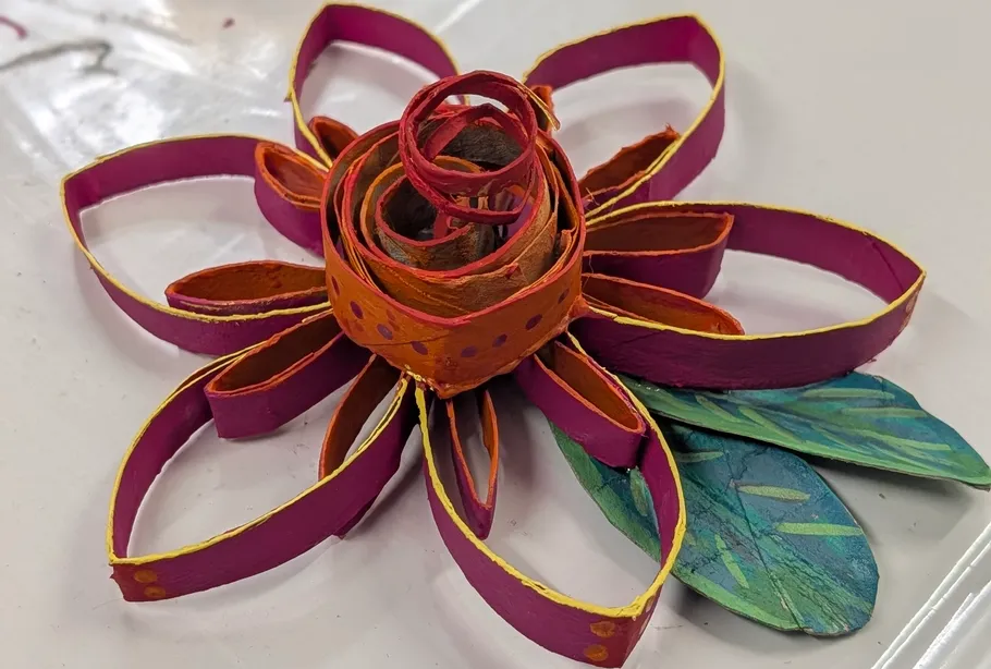 Bunte Papierblume auf weißer Oberfläche.