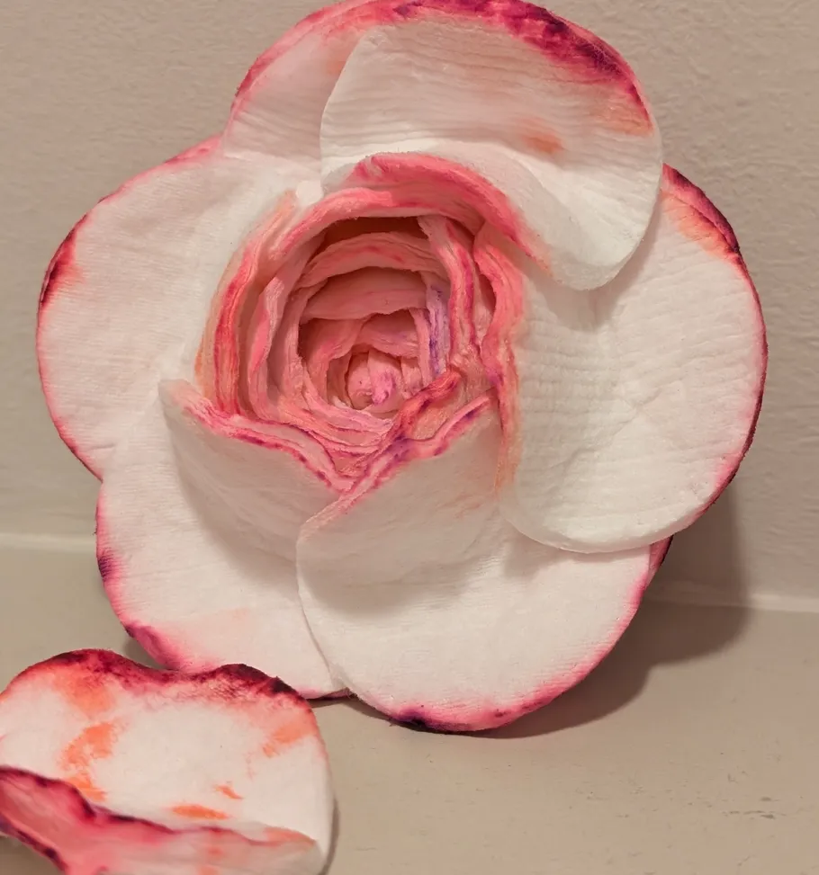 Weiß-pinke Papierblume auf beigem Hintergrund.