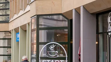 Person walking past coffee shop entrance.