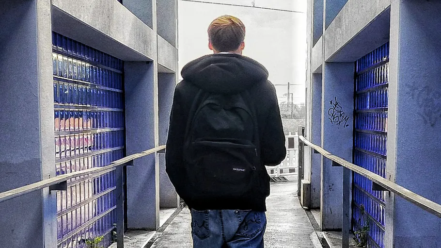 Person geht auf einem schmalen Weg zwischen Glaswänden.