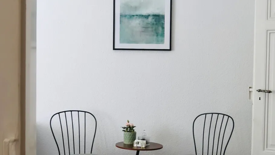 Zwei Stühle und Tisch in minimalistischem Raum.