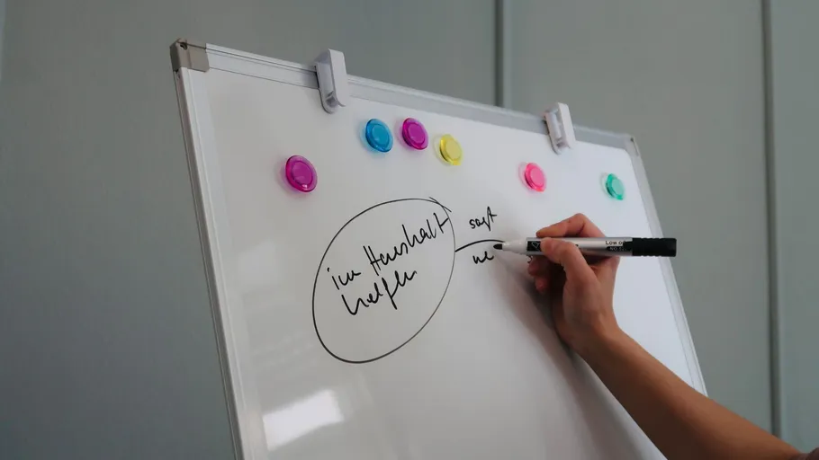 Hand schreibt auf Whiteboard im Büro.