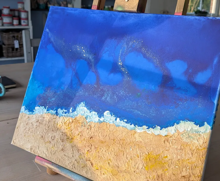 Abstract beach painting displayed on easel.