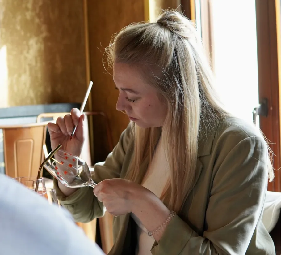 Woman painting a wine glass indoors.