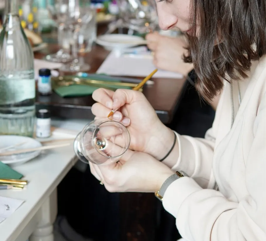 Person painting glass at a table.