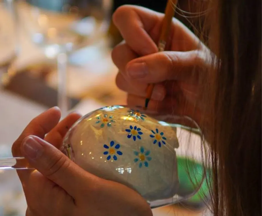 Hände bemalen Blumen auf Glas im Workshop.