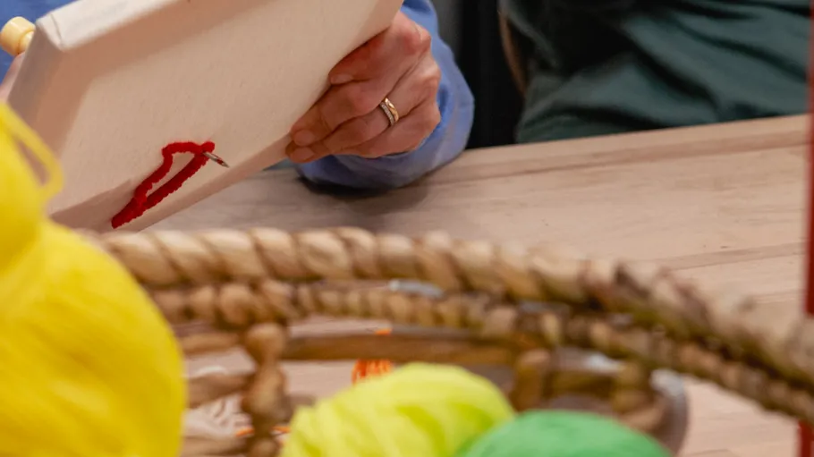 Person embroidering with red thread on fabric.