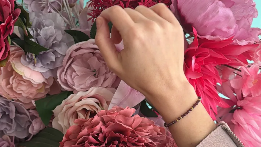 Hand reaching towards colorful flowers.