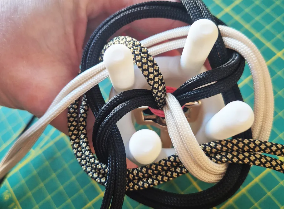 Hand holding intertwined cords on a board.