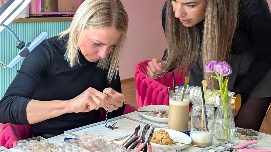 Two women crafting jewelry at a table.