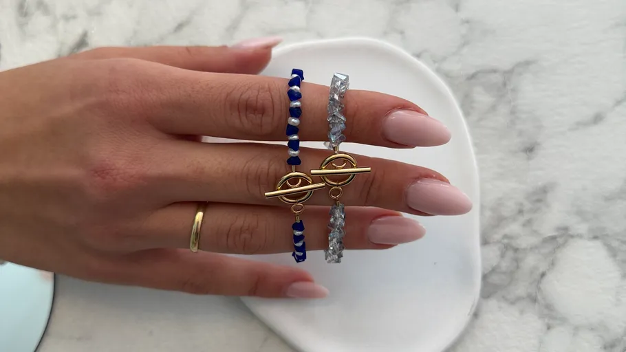 Hand with bracelets on marble surface.