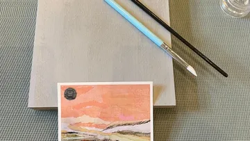 Zwei Pinsel auf Holz mit Kunstkarte.